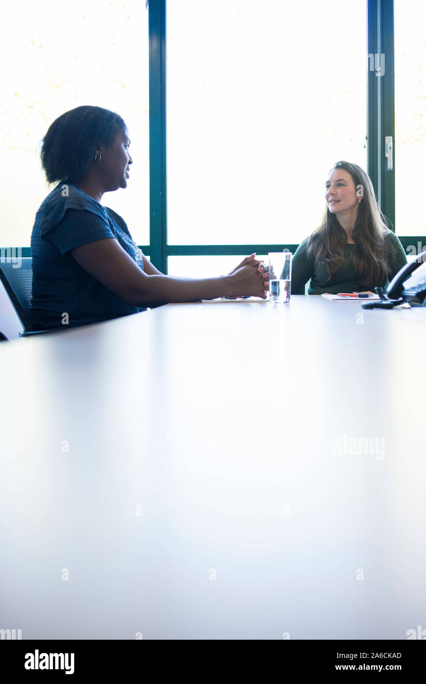 Eine schwarze Frau sitzt an einem Tisch in einer Chancengleichheit Business Stockfoto