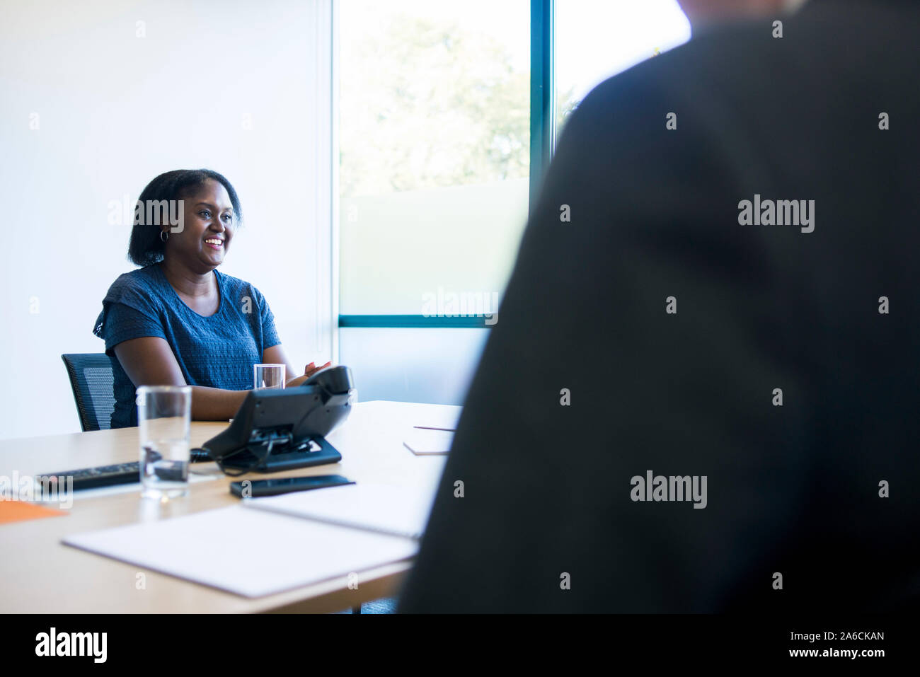 Eine schwarze Frau sitzt an einem Tisch in einer Chancengleichheit Business Stockfoto