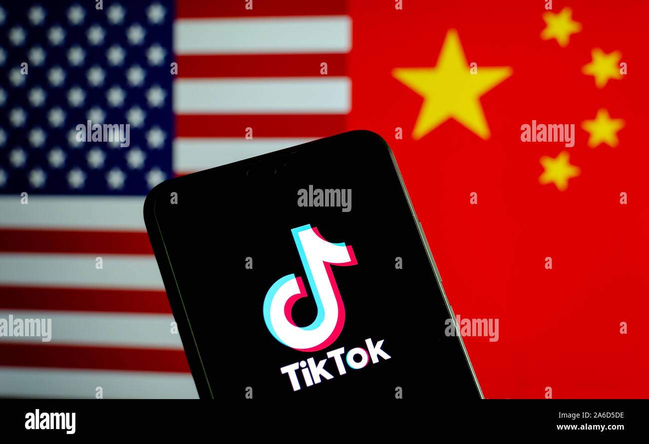 TikTok app Logo auf einem Bildschirm des Smartphones und Fahnen von China und USA auf die verschwommenen Hintergrund. Die App ist in der Mitte der Spannungen zwischen den USA und China. Stockfoto