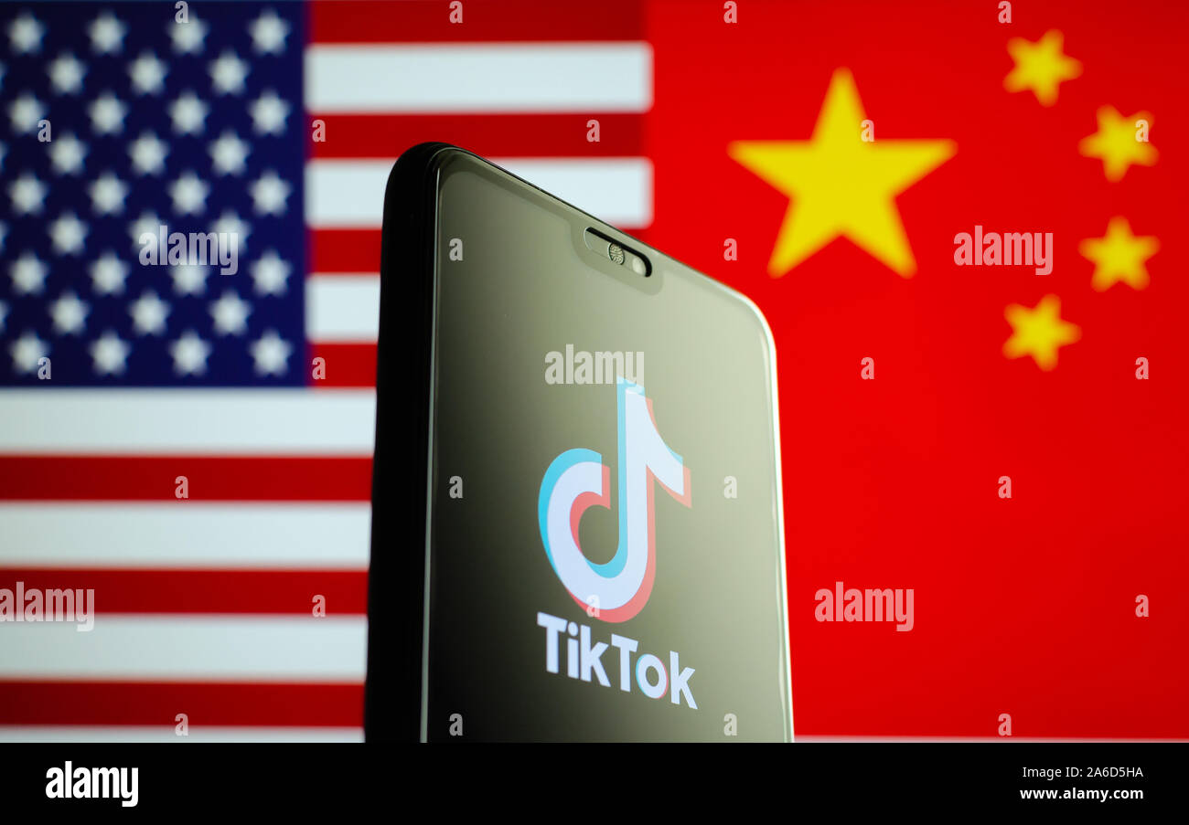 TikTok app Logo auf einem Bildschirm des Smartphones und Fahnen von China und USA auf die verschwommenen Hintergrund. Die App ist in der Mitte der Spannungen zwischen den USA und China. Stockfoto