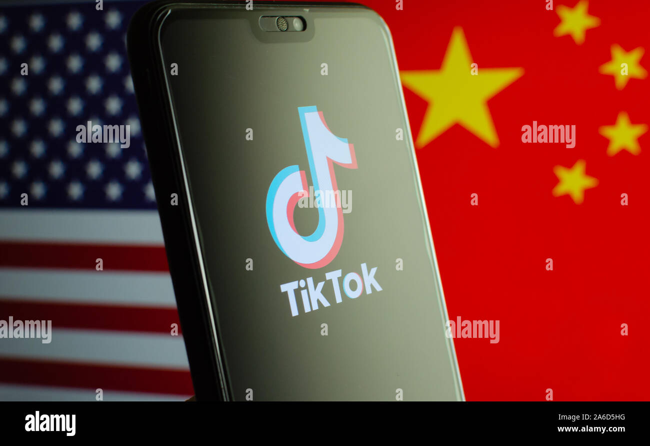 TikTok app Logo auf einem Bildschirm des Smartphones und Fahnen von China und USA auf die verschwommenen Hintergrund. Die App ist in der Mitte der Spannungen zwischen den USA und China. Stockfoto