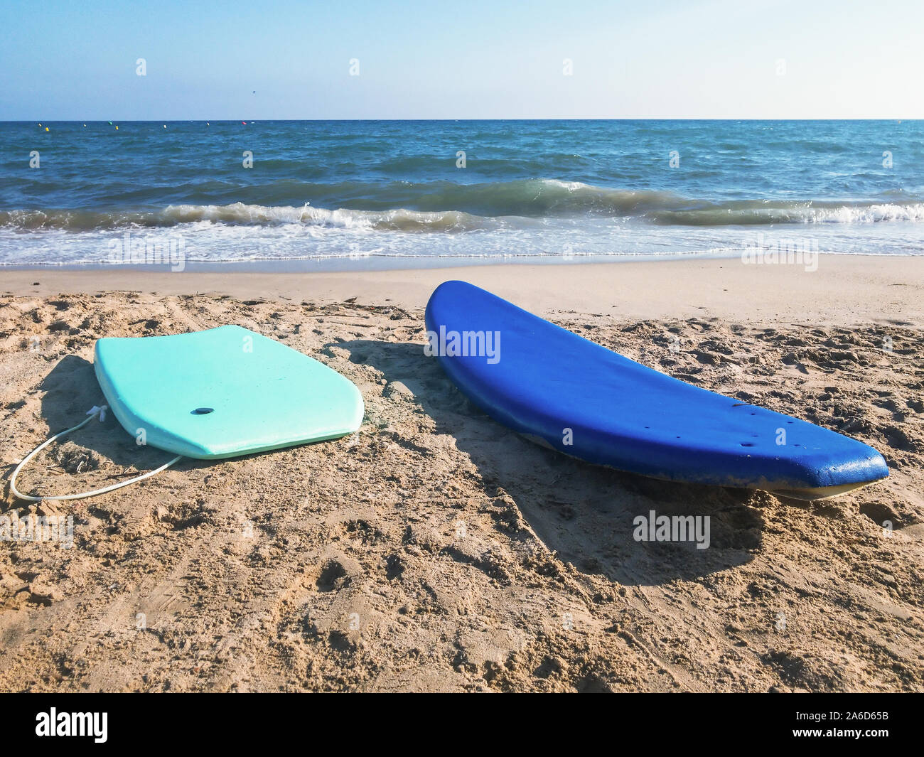 Wasser Surfbretter Blau und Türkis auf der sandigen Küste mit blauen Wasser unter der endlosen blauen Himmel Stockfoto