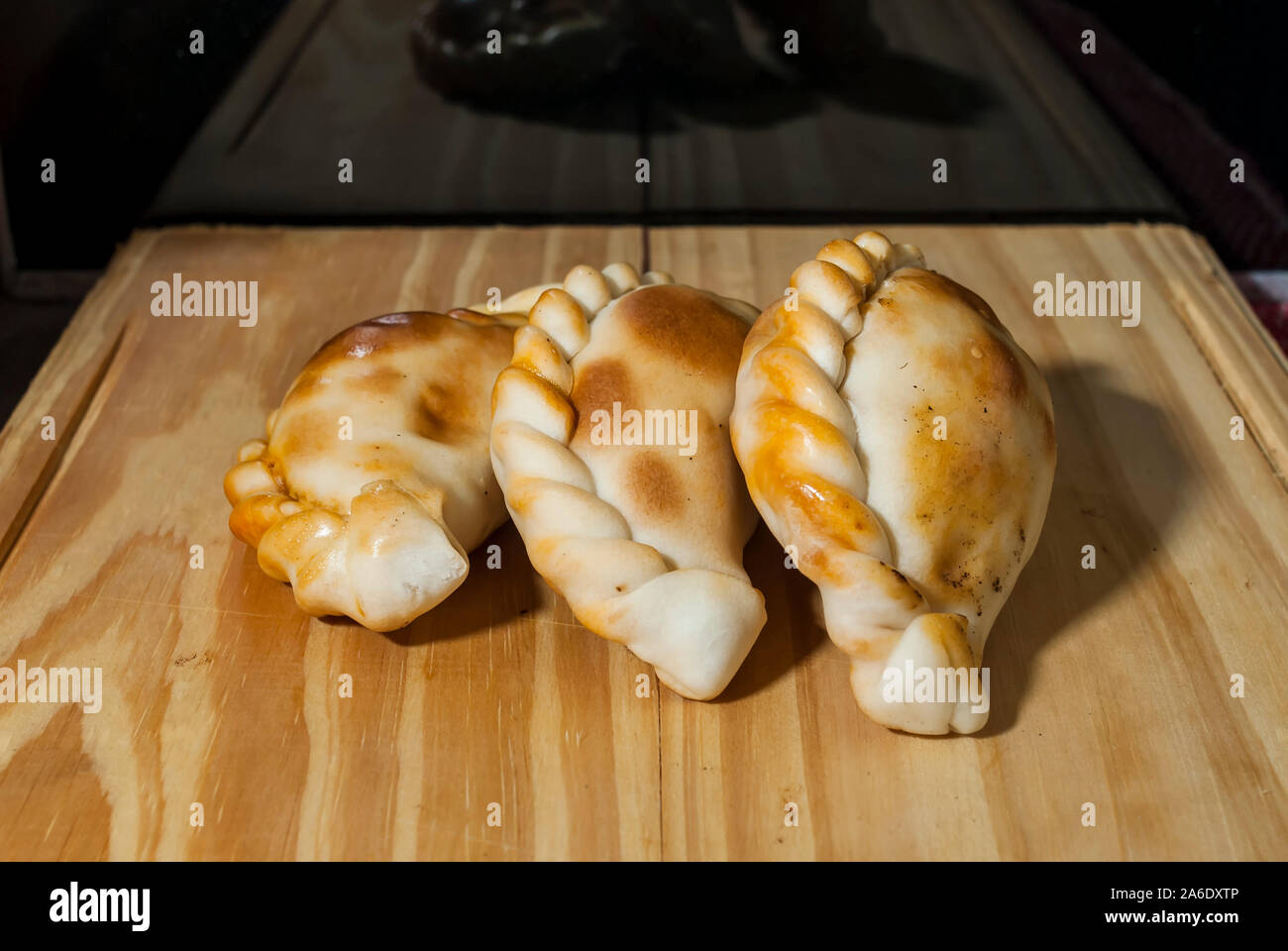 Holztisch mit frischen, hausgemachten Empanadas (detaillierte Nahaufnahme; selektive Fokus) Stockfoto