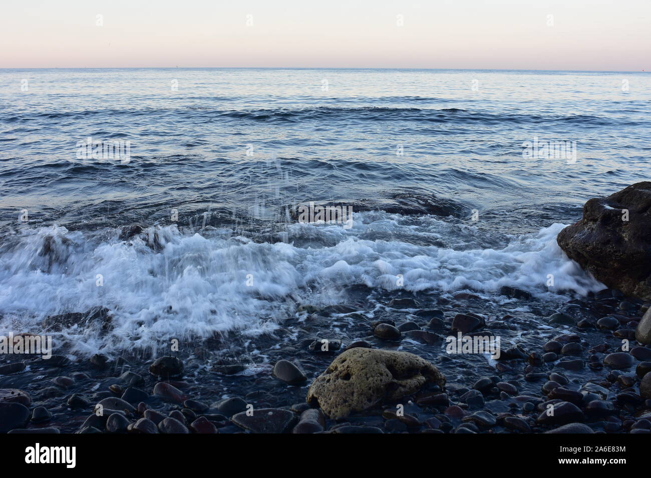 Milde surfen am Strand von schwarzen vulkanischen Kieselsteinen im Osten der Insel Bali. Stockfoto