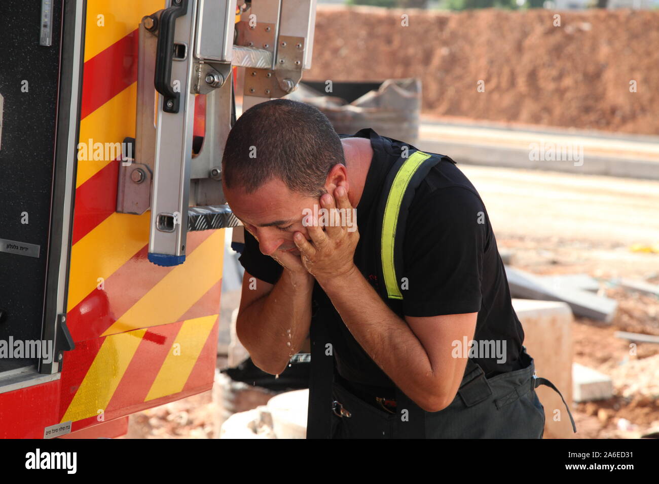 Mutige Feuerwehrmann wäscht sein Gesicht nach einer langen und schwierigen Bohren in heißem Wetter, GIVAT SHMUEL, ISRAEL Stockfoto