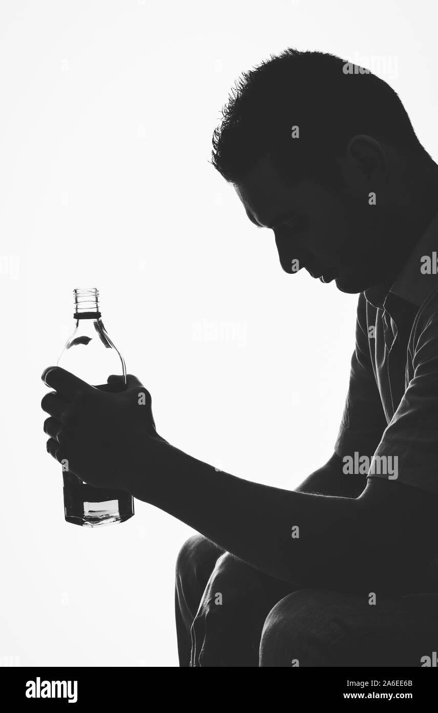 Die Silhouette im Schatten der Mann hält eine Flasche Schnaps auf Weiß. Von der Seite. Stockfoto