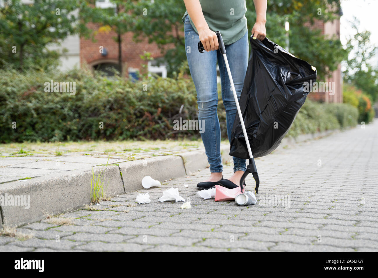 Frau sammeln Müll im Freien mit Wurf Picker Stockfoto