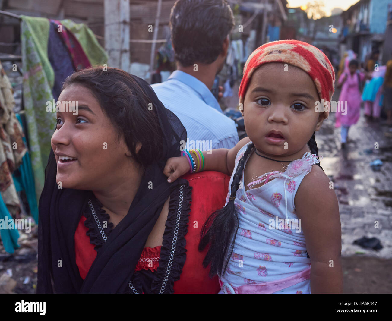 Ein junger indischer Mutter ihre Durchführung nattily gekleidet baby Tochter throght Darukhana Slumgebiet, Mazgaon, Mumbai, Indien Stockfoto