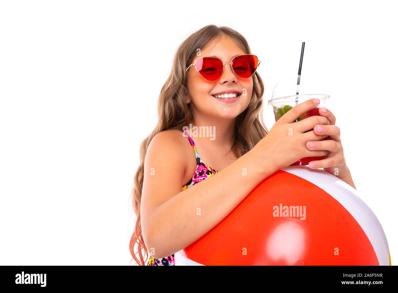 Mädchen mit langen gekreuzigt Haar in Sonnenbrille und Sonnencreme, steht in der Nähe von aufblasbaren Matratzen mit frischen Fruchtcocktail auf weißem Hintergrund Stockfoto