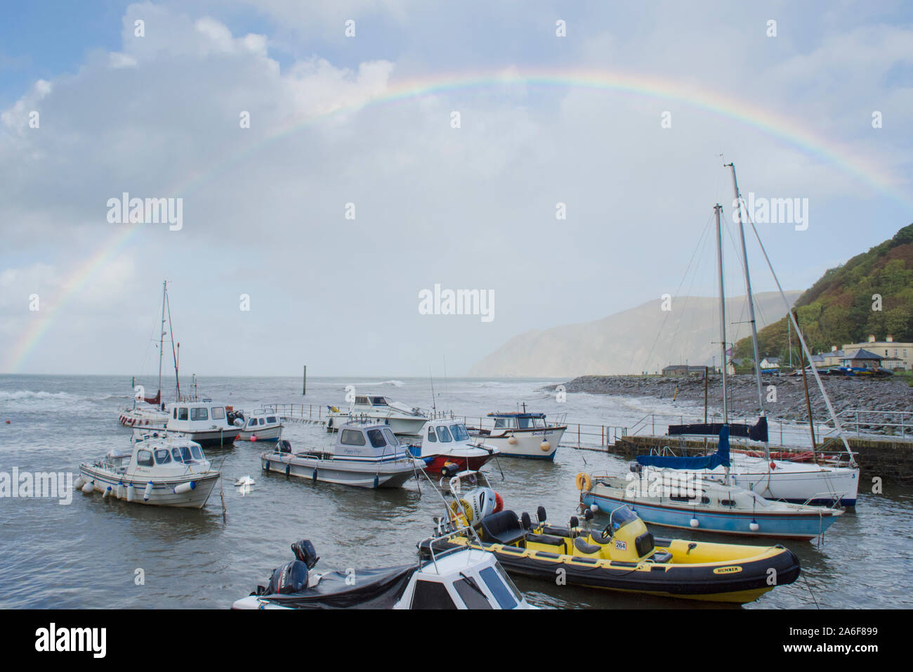 Regenbogen über dem Meer, Boote, Hafen und Strand in Lynmouth bei stürmischem Wetter, Devon, UK, September. Höhe Tide,, Stockfoto