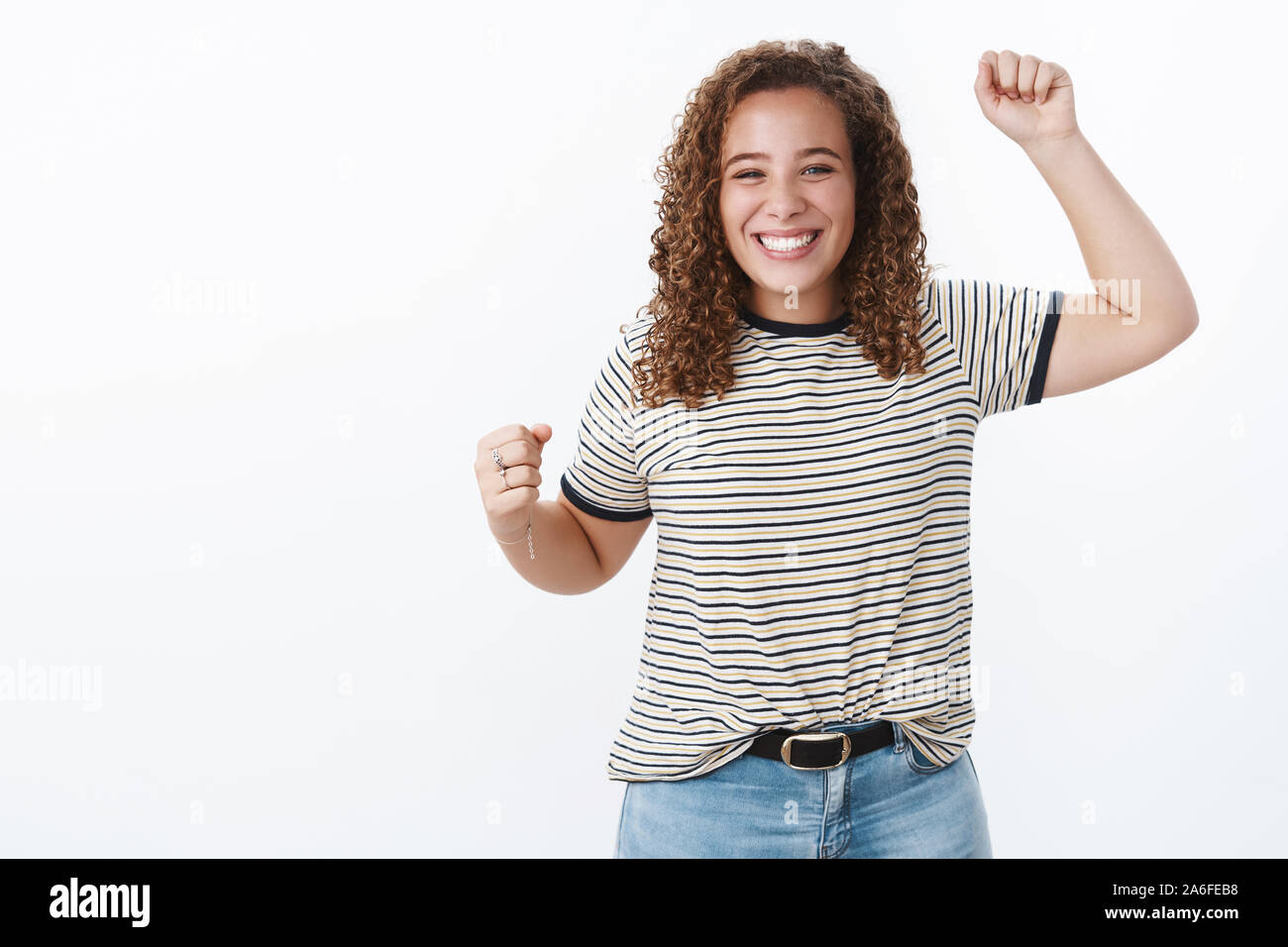 Ja sie es tat, feiern Sie zusammen mit Freunden. Charmante triumphierte freudigen freundlichen jungen curly-behaarten Körper - positive Mädchen lächelnd Ziel erreichen anheben Stockfoto