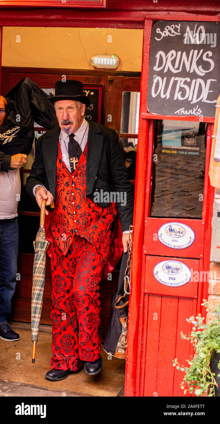 Mann in Rot traditionelle Goth Kostüm beenden roten Türen von Shop, Whitby Goth Wochenende Festival, Whitby, North Yorkshire, UK, 26. Oktober 2019 Stockfoto