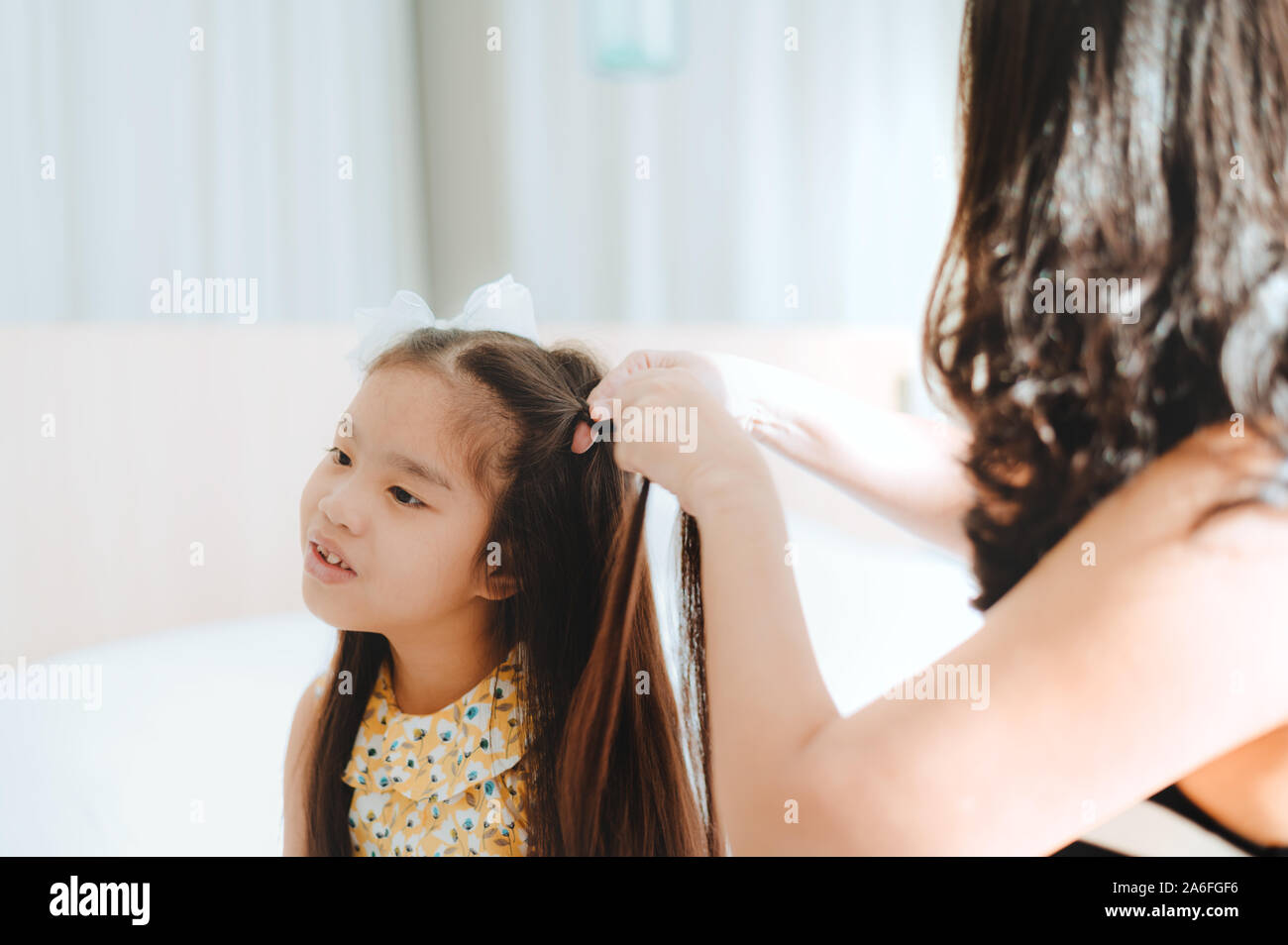 Asiatische Mutter kämmen Tochter im Bett Stockfoto