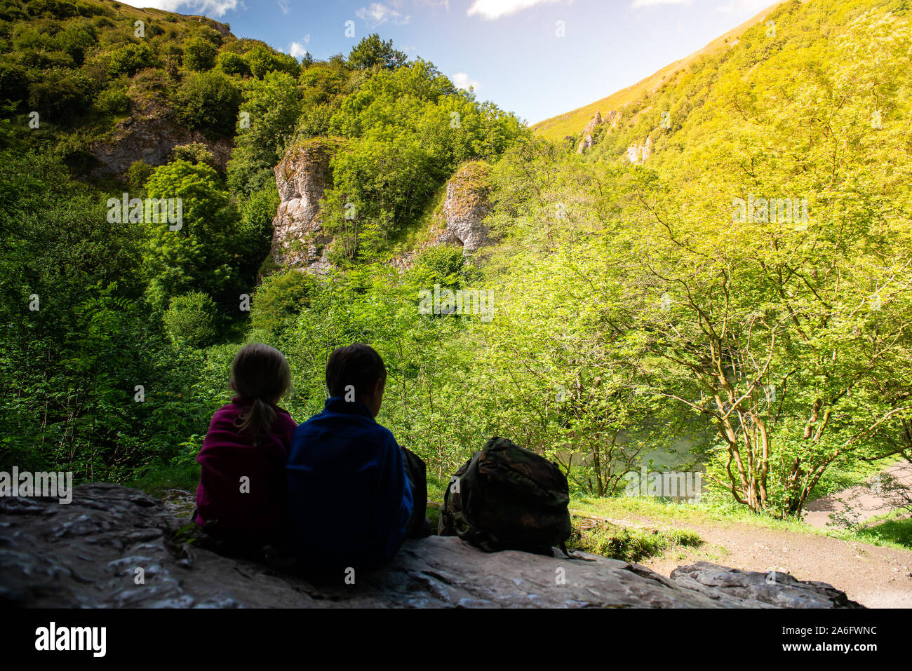 Einen kleinen Jungen mit ADHS, Autismus, Asperger-syndrom, Bruder und Schwester sitzen in einer Höhle hoch in die Berge und bewundern Sie die Aussicht während der Re Stockfoto