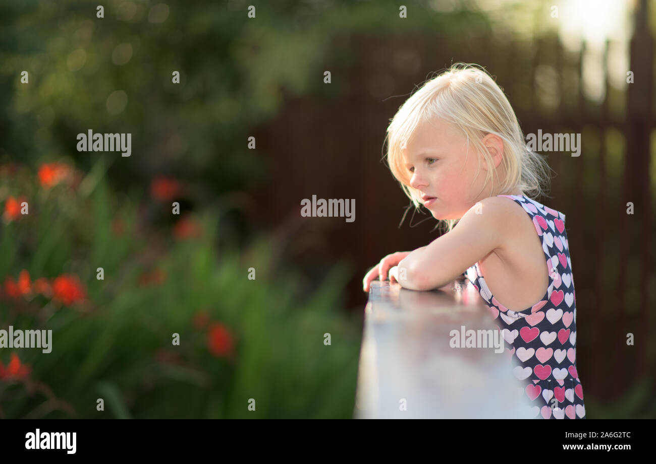 Ein hübsches kleines blondes Mädchen in die Kamera, während auf einer Brücke, starrt Stockfoto