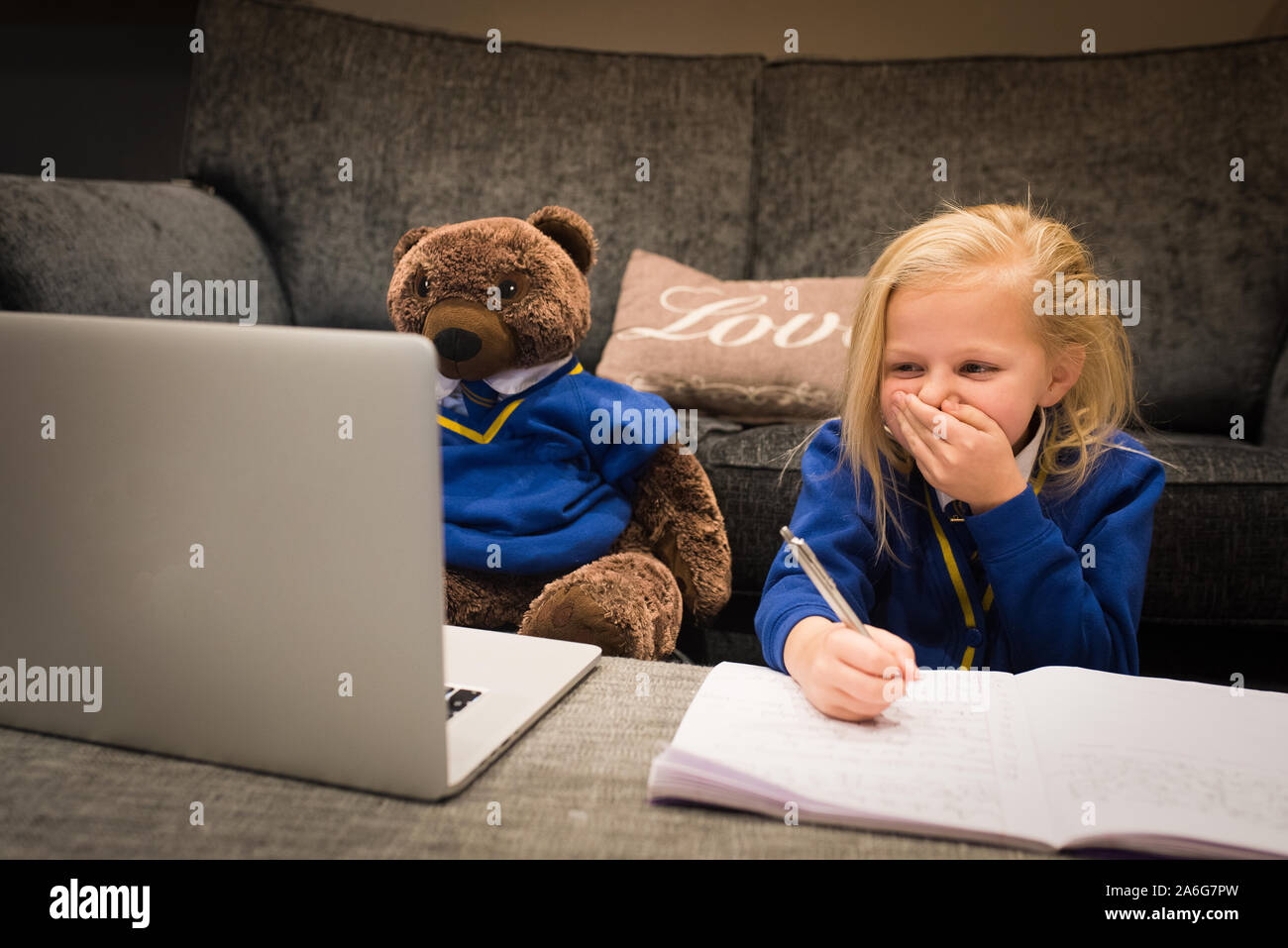 Ein süßes kleines Mädchen hat ihre Schule home Arbeit mit ihrer Schule tragen für eine Hausaufgaben Projekt, Spaß Erziehung , Bildung, Humor Stockfoto
