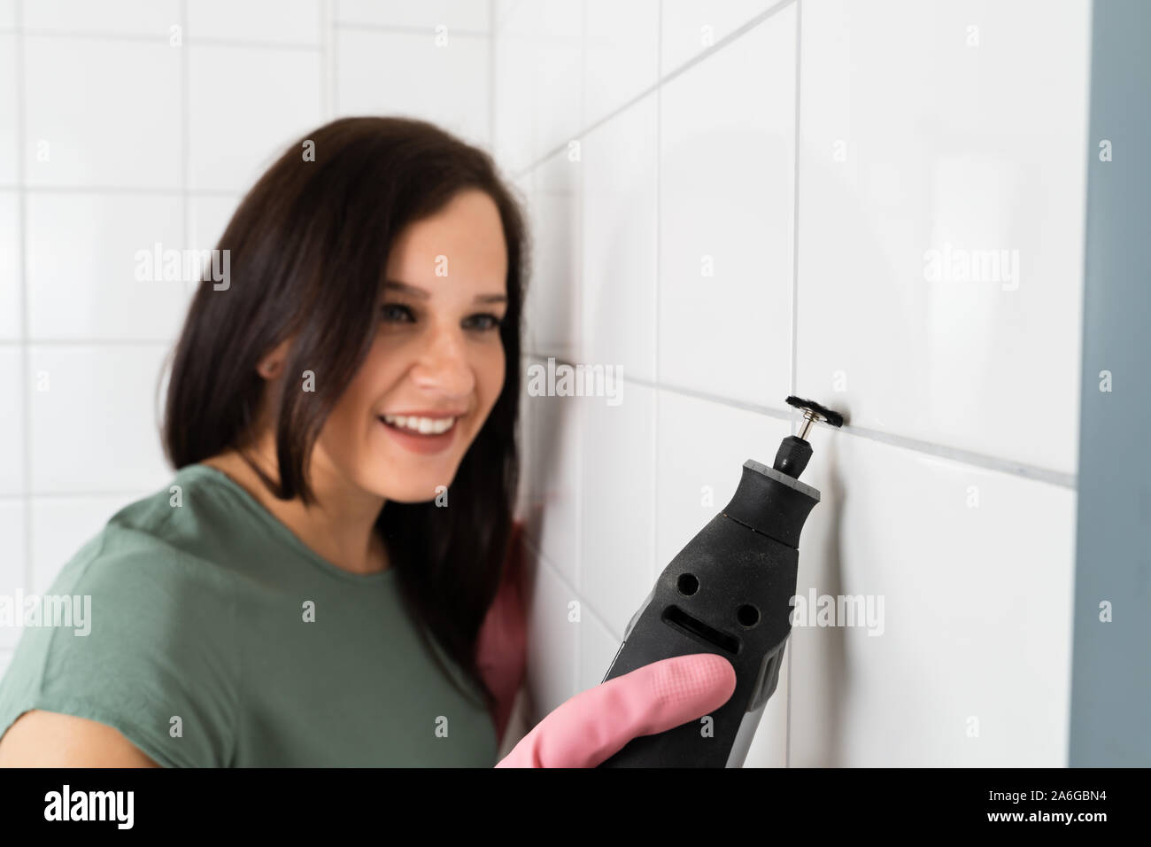 Person Reinigung der schmutzigen weißen Fliesen der Wand mit Power Tool Stockfoto