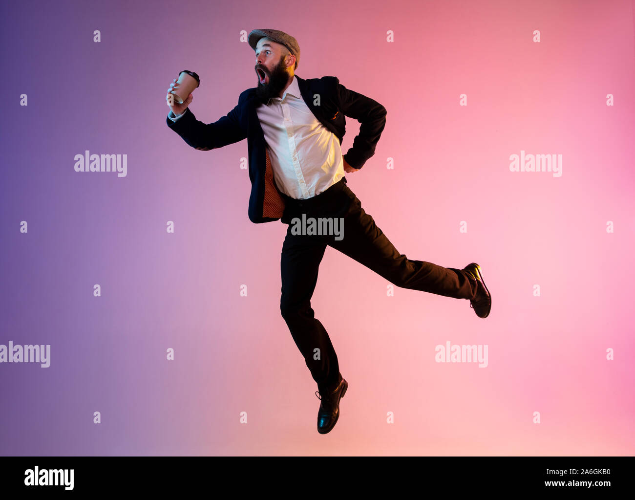 Volle Länge Portrait von Happy jumping Mann, Büro Kleidung im Neonlicht auf Farbübergang Hintergrund isoliert. Emotionen, Ad-Konzept. Sich beeilen, zu spät zur Arbeit oder Verkauf, shopping. Getränke Kaffee trinken gehen. Stockfoto