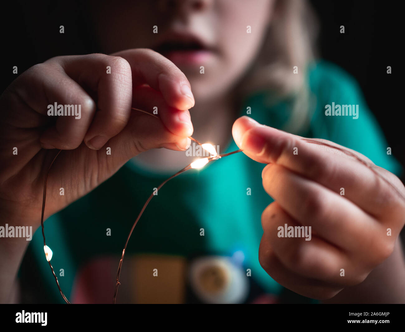 4-Jähriges Mädchen berühren zwei Teile eines Kupfer LED-string Stockfoto