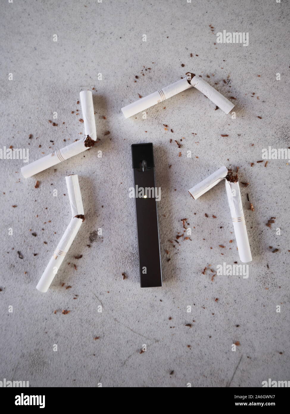 Vape Gerät Elektronische Zigarette Juul, wie Rauchen alternative mit gebrochenen Marlboro Gold Zigaretten und Tabak verstreut auf Weiß strukturierten Hintergrund Stockfoto