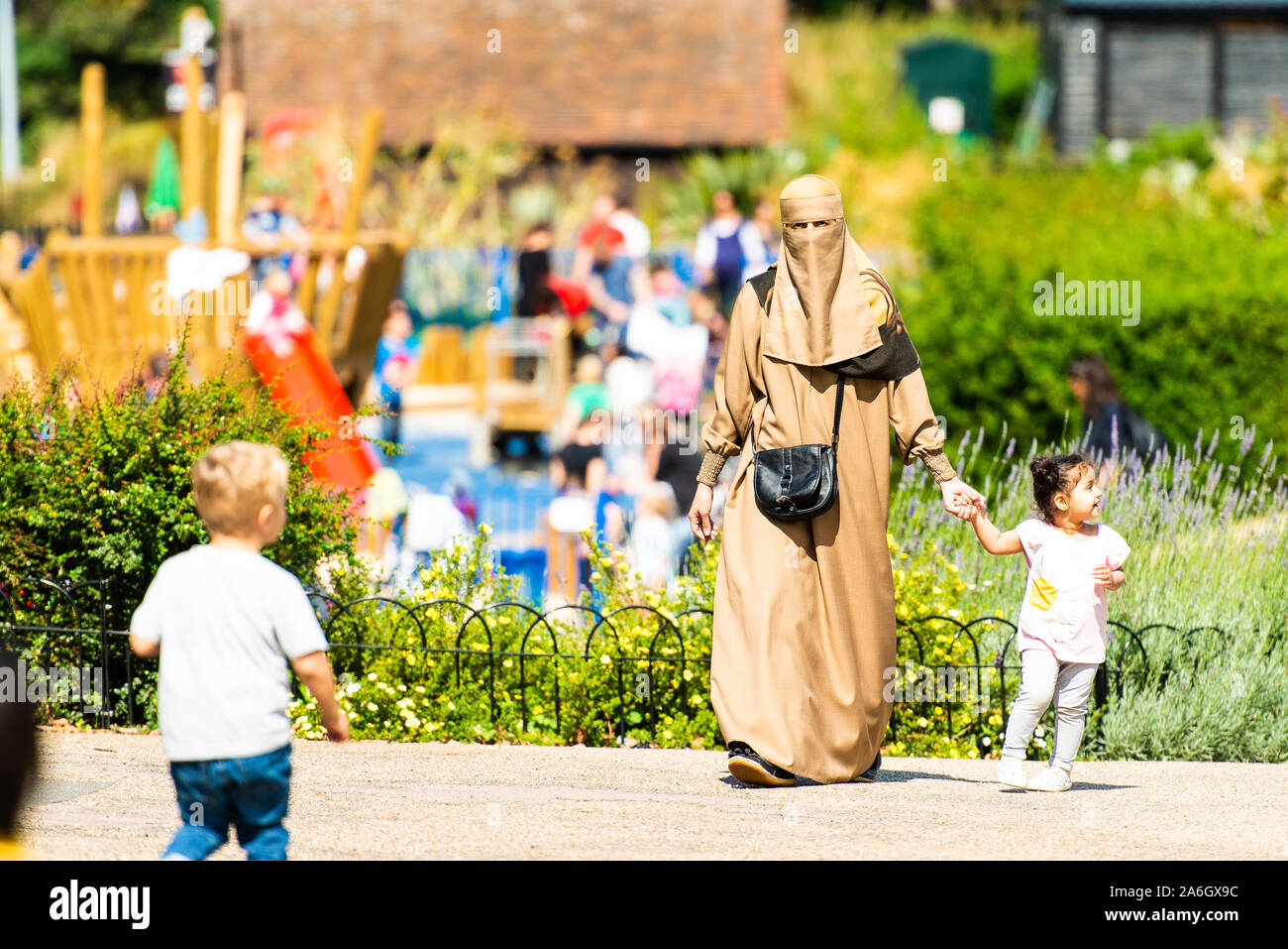 Ein muslimischer Frauen in eine Burkha, Hijab gehen mit ihrem Kind in Colchester Castle Park, Essex, Kultur, Religion, Multikulturalismus Stockfoto