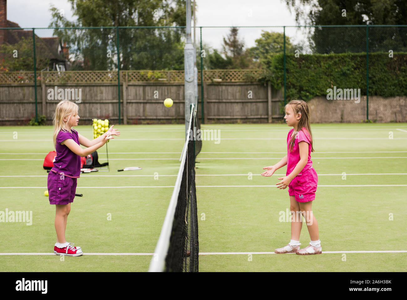 Zwei junge Mädchen üben Ihre Tenniskünste auf lokaler Tennis Club, Hof Stockfoto