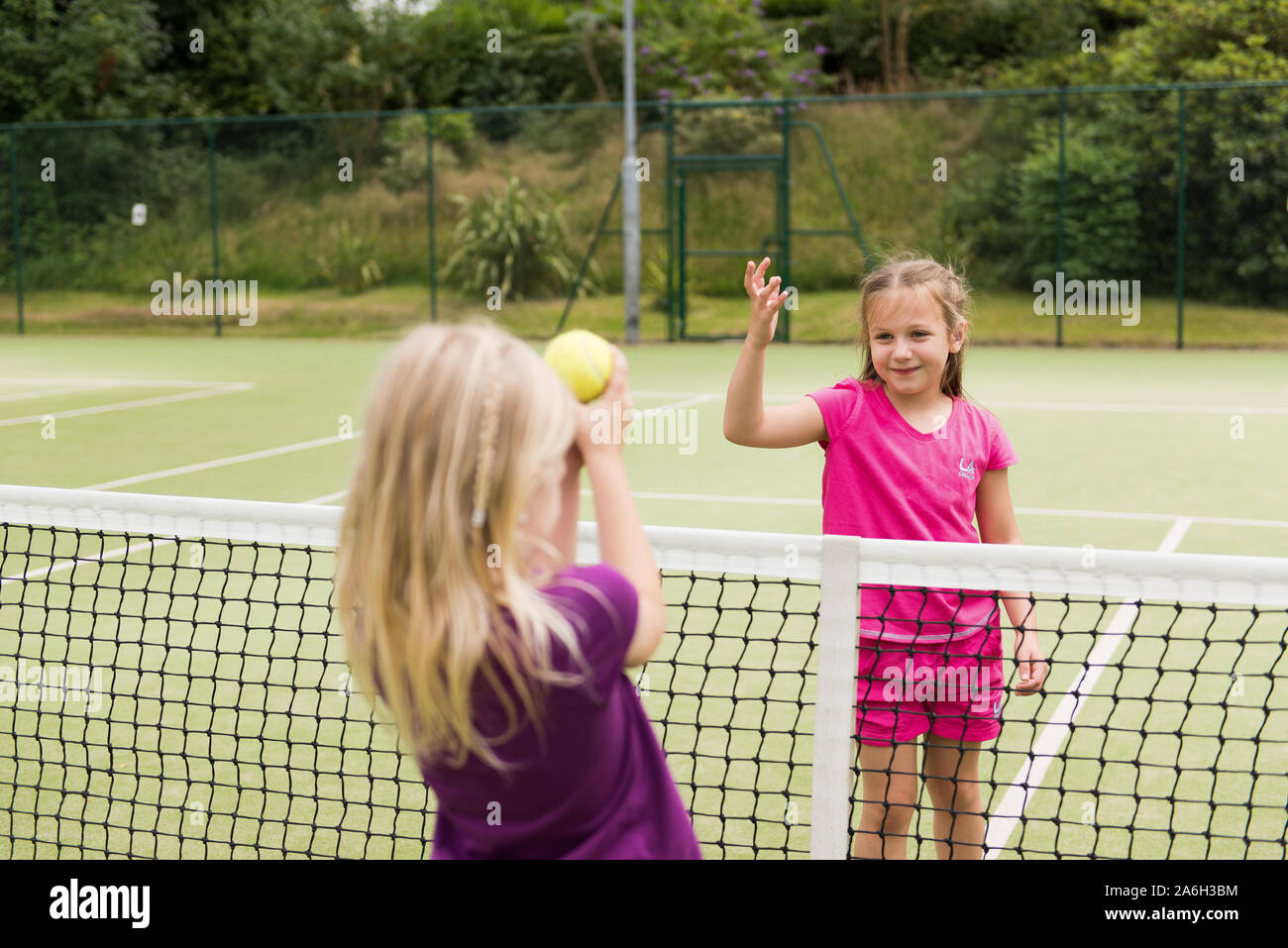 Zwei junge Mädchen üben Ihre Tenniskünste auf lokaler Tennis Club, Hof Stockfoto