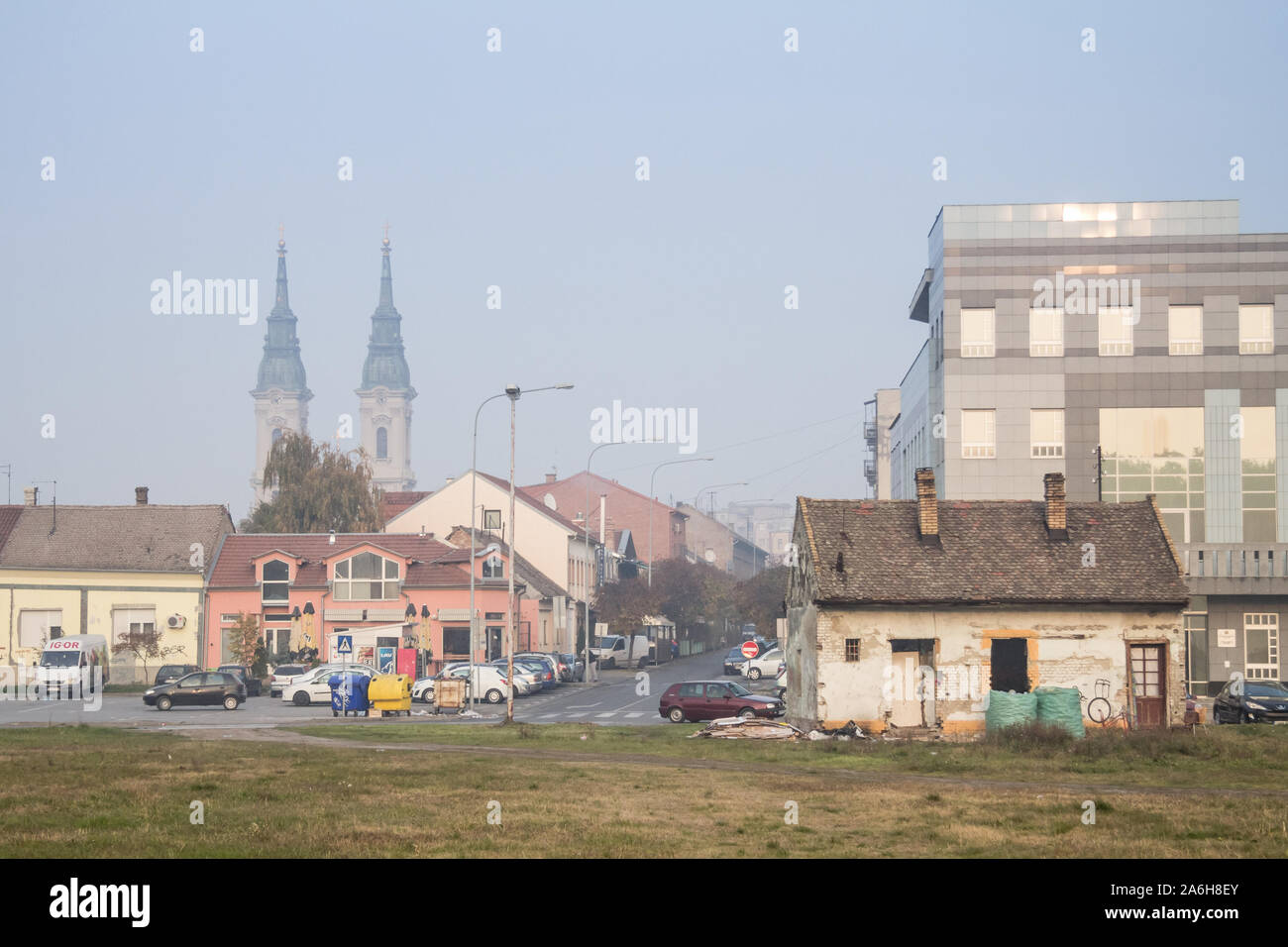 PANCEVO, Serbien - NOVEMBER 7, 2015: Panorama der Pancevo vom Stadtpark mit einem alten Haus in Verfall vor und die Uhr Türme der lokalen Stockfoto