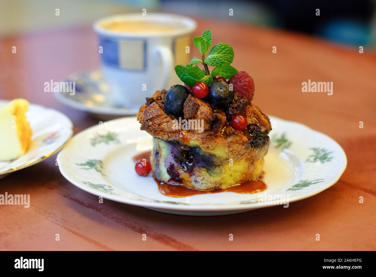Ein schöner, frischer Kuchen mit Beeren, mit Minze in prächtigen Geschirr auf einen hölzernen Tisch serviert dekoriert. Berry Brotpudding. Stockfoto