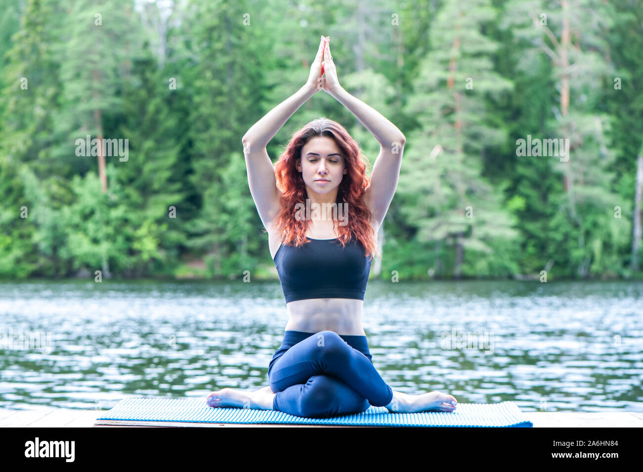 Junge yogi Mädchen üben Yoga, in Variation von Gomukhasana, Kuh Gesicht Körperhaltung sitzen auf dem Pier von einem schönen See. Konzept des gesunden Lebens und Stockfoto