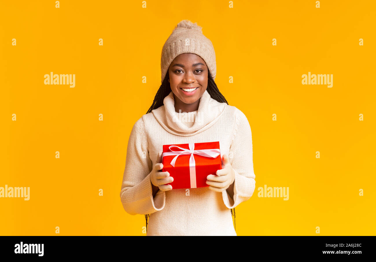 Schöne afro Girl im Winter Mütze und Handschuhe holding Geschenk Stockfoto