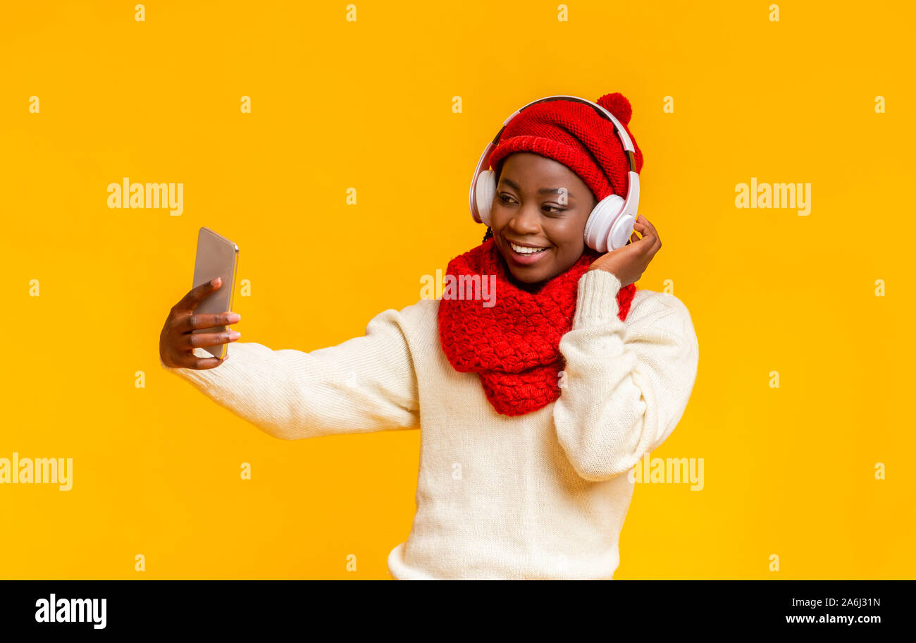 Freundliche schwarze Mädchen im Winter Hut und Headset unter selfie Stockfoto
