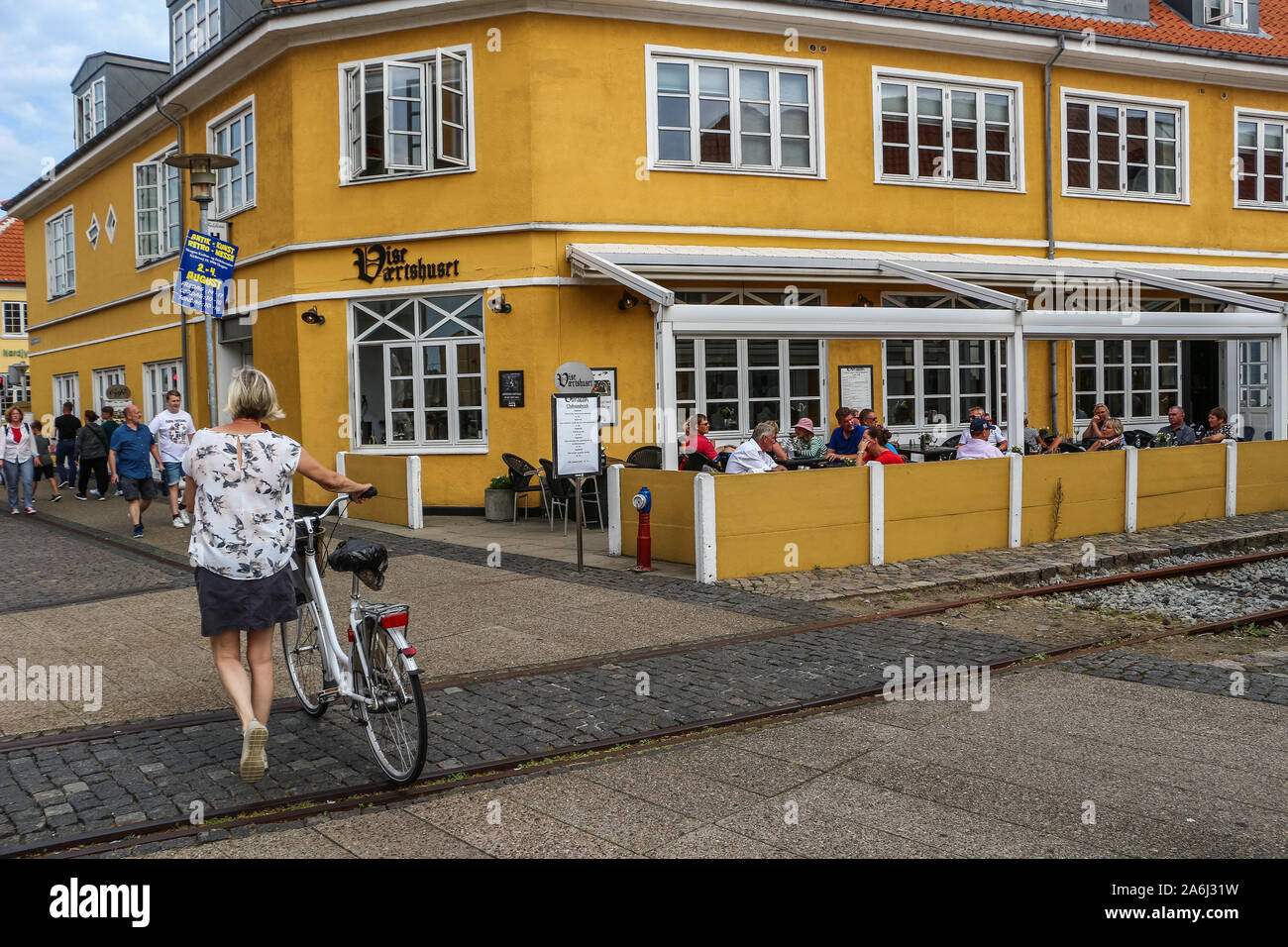 Frau mit einem Fahrrad zu Fuß vor dem Restaurant ist in Skagen, Dänemark am 28. Juli 2019 Skagen ist die nördlichste Stadt Dänemarks, an der Ostküste der Halbinsel Skagen Odde ganz im Norden von Jütland. © Michal Fludra/Alamy leben Nachrichten Stockfoto
