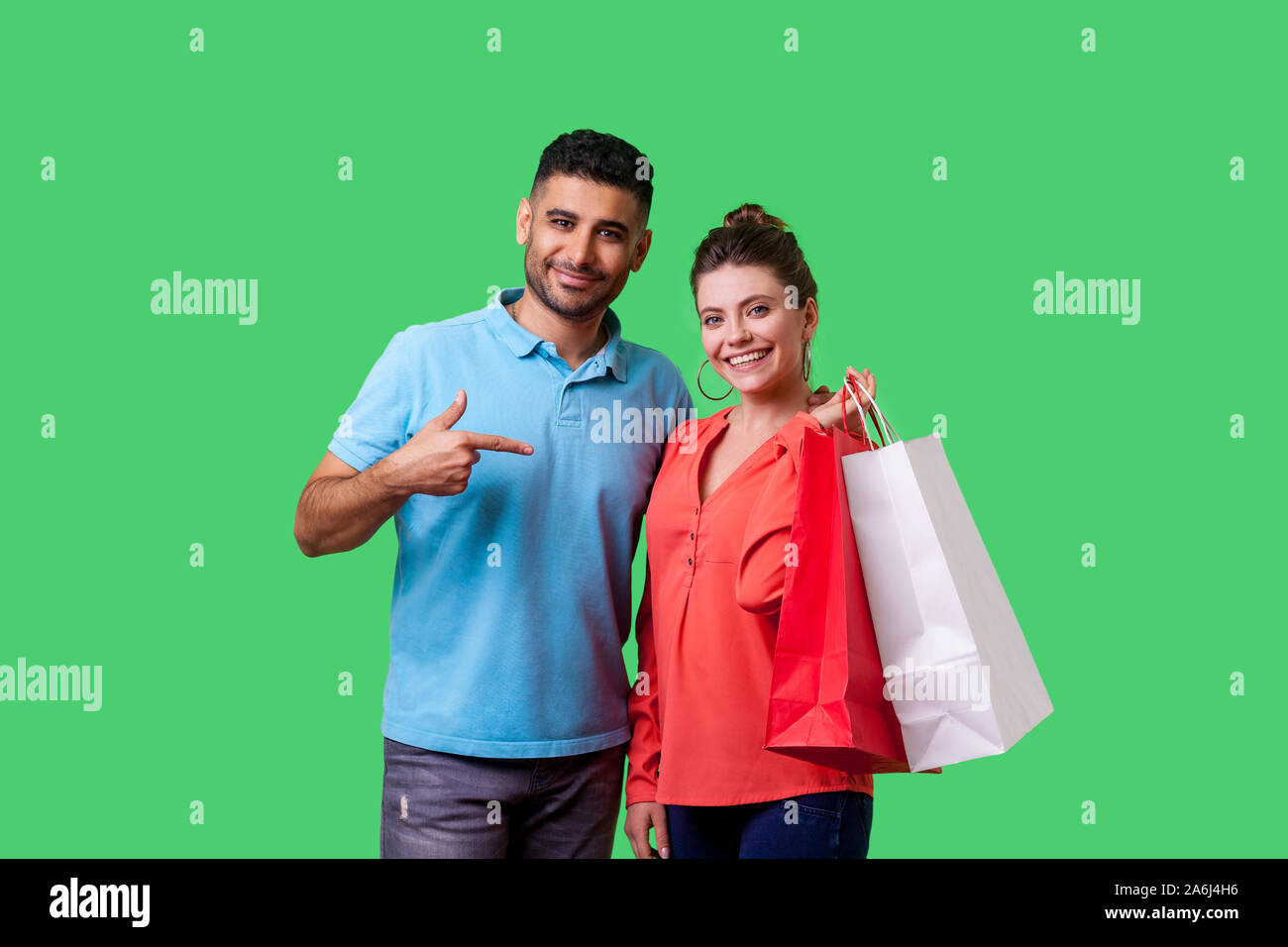 Zufriedene Käufer. Portrait von Happy bärtiger junger Mann in Freizeitkleidung auf Einkaufstüten, der in die Hände der aufgeregten Frau, mit Ermäßigungen. iso Stockfoto