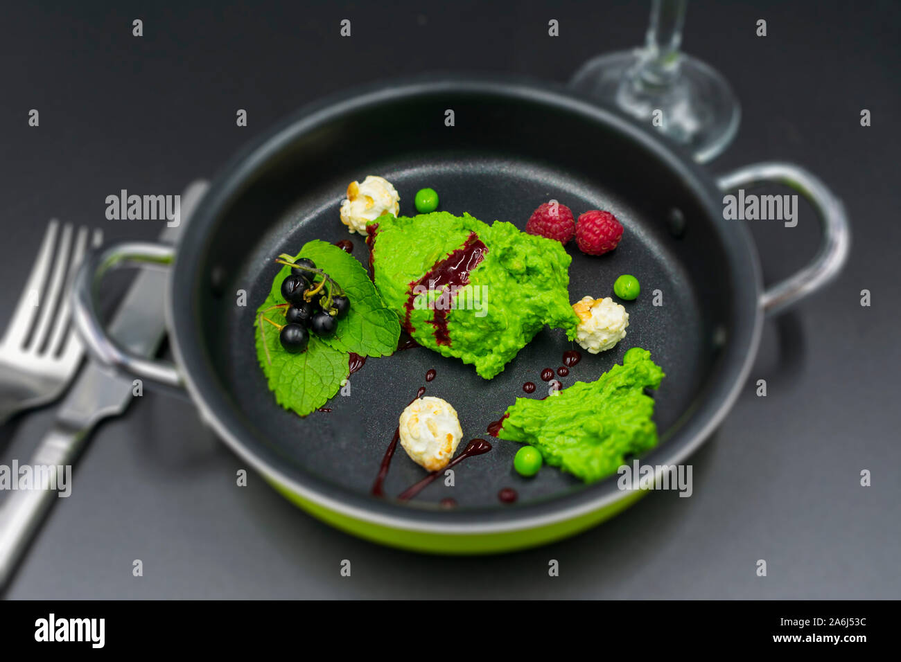 Pea Sorbet mit Minze, Beeren und Popcorn mit unscharfem Hintergrund. Stockfoto