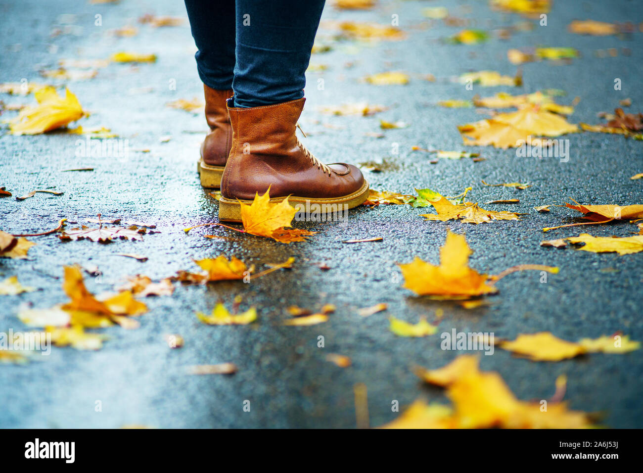 Spaziergang auf dem nassen Bürgersteig. Zurück Blick auf den Füßen einer Frau, die auf dem Asphalt mit Pfützen im Regen. Paar Schuhe auf glatter Straße in Th Stockfoto