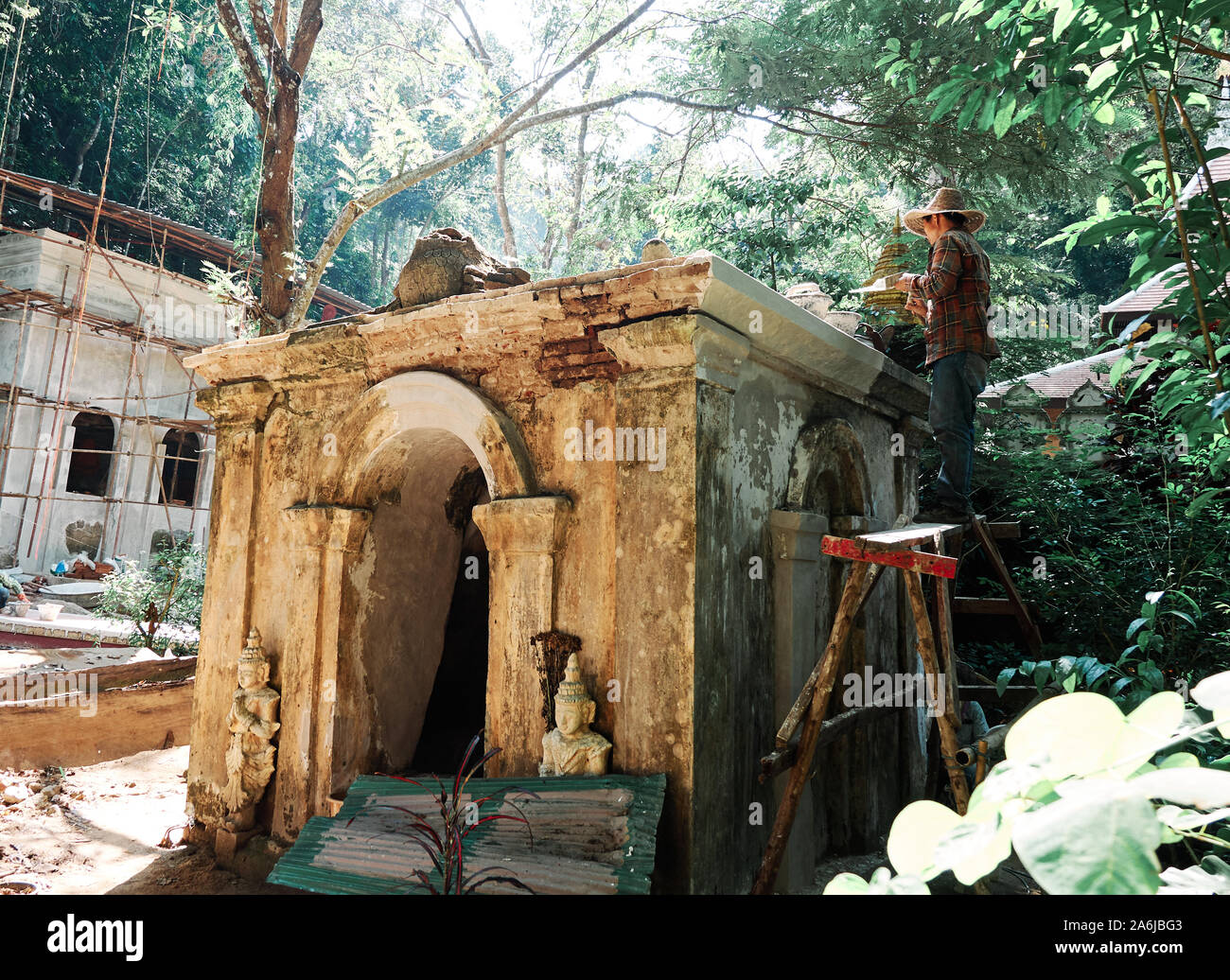 Restaurierungsarbeiten durchgeführt, die von einem Arbeiter auf verborgenen Dschungel Tempel von Wat Pha Lat in Chiang Mai, Thailand. Stockfoto