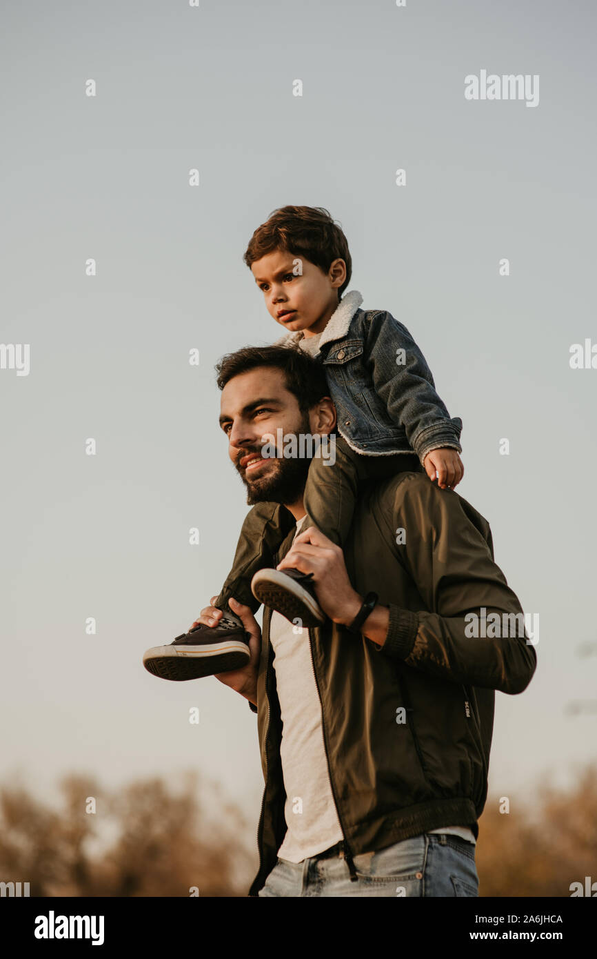 Gerne Vater Sohn Fahrt auf seinen Schultern während des Gehens im Herbst Park. Stockfoto