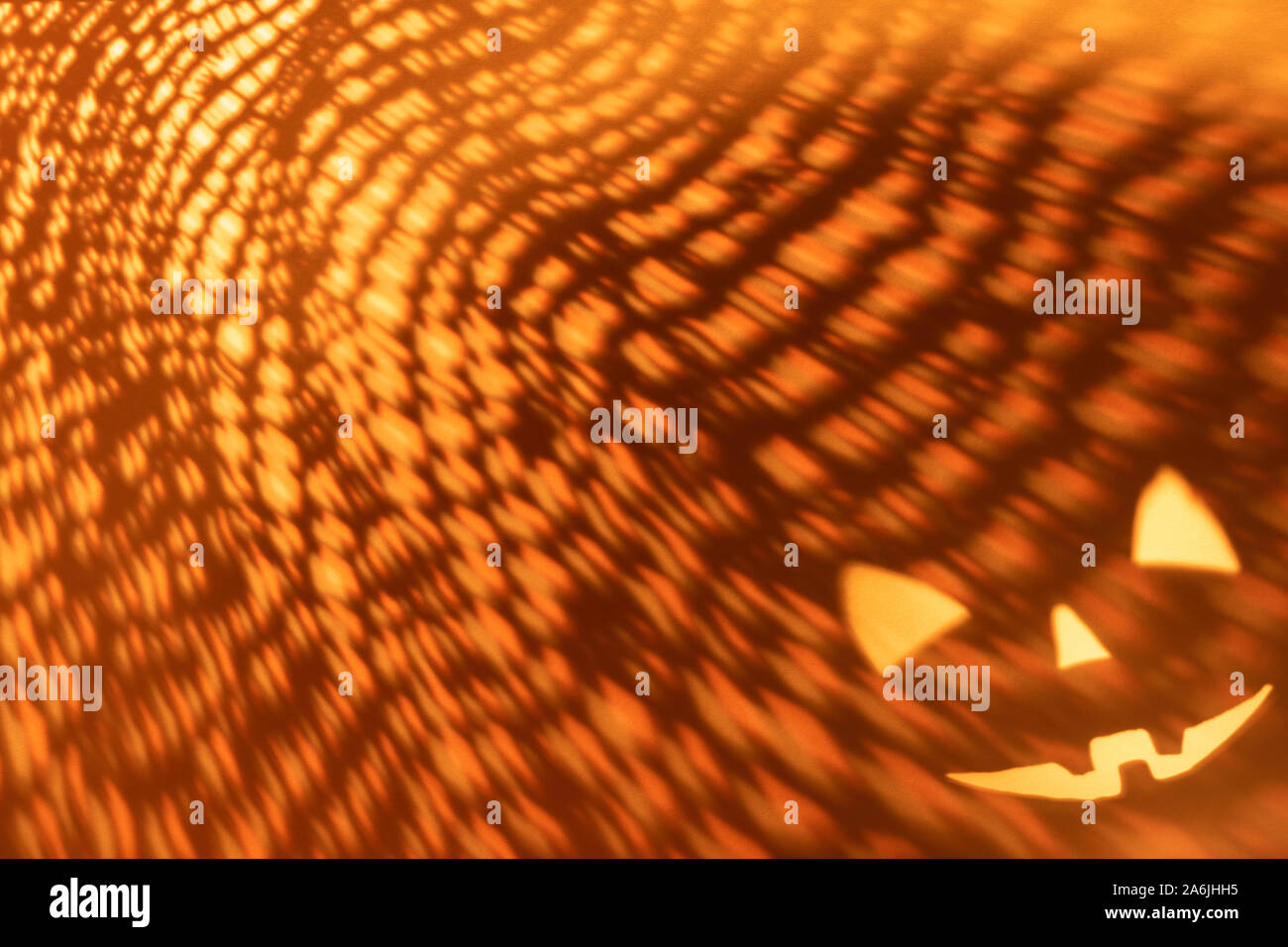 Halloween scary pumpkin Gesicht auf dunklen orange Papier Hintergrund. Schatten aus dem Feuer. Halloween Horror Hintergrund. Stockfoto