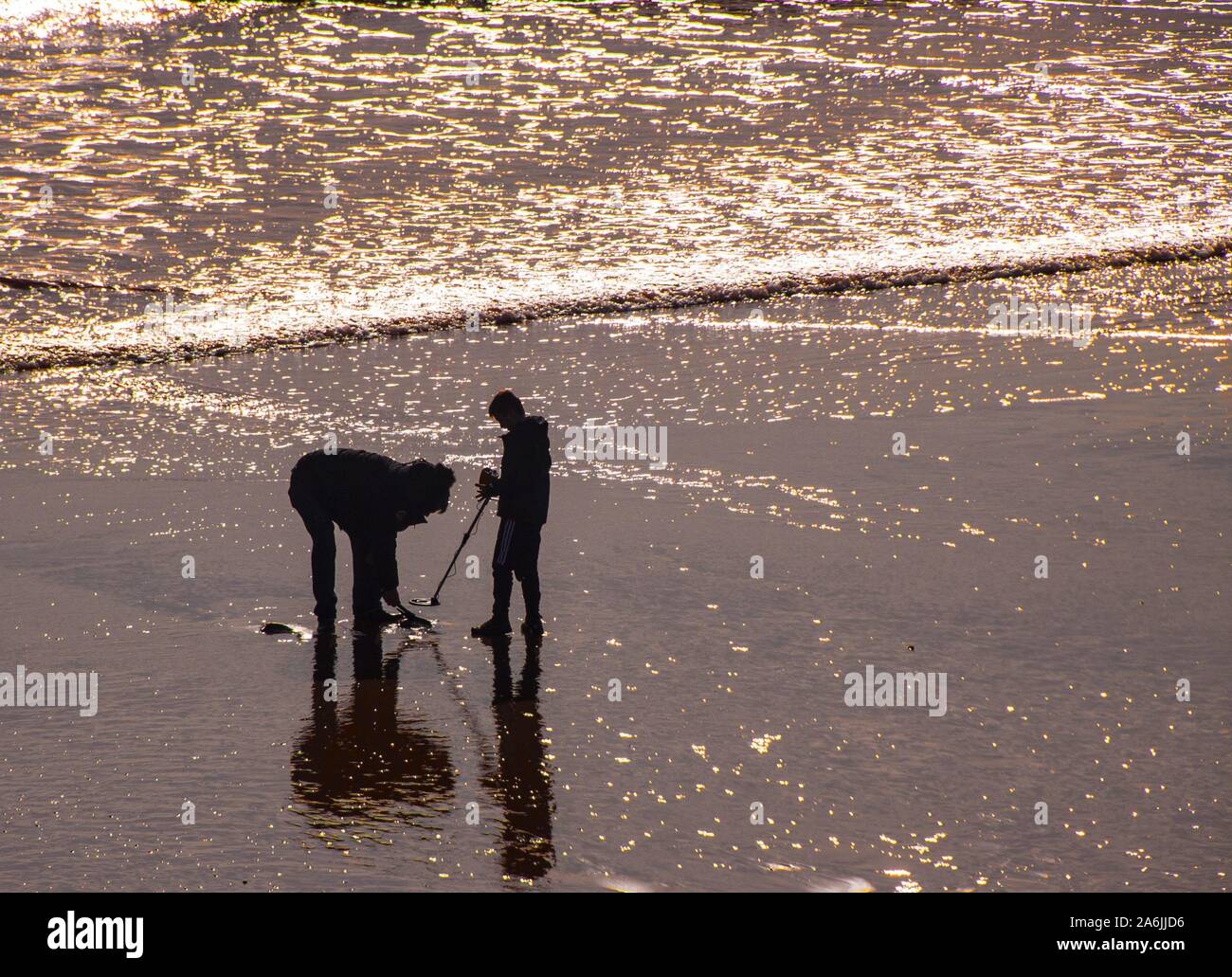 Sidmouth, Großbritannien. 27 Okt, 2019. Eine Familie versuchen Sie ihr Glück mit einem Metalldetektor am Strand von Sidmouth an einem sonnigen, aber kalten Tag an der Küste von Devon. Credit: Foto Central/Alamy leben Nachrichten Stockfoto