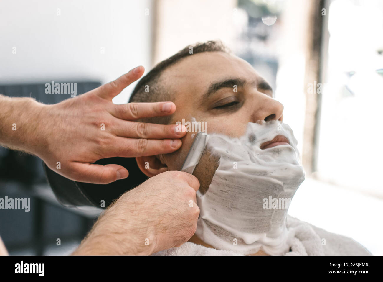 Friseur rasiert einen Bart zu einem Mann mit einem Rasiermesser in einem  Barbershop Stockfotografie - Alamy