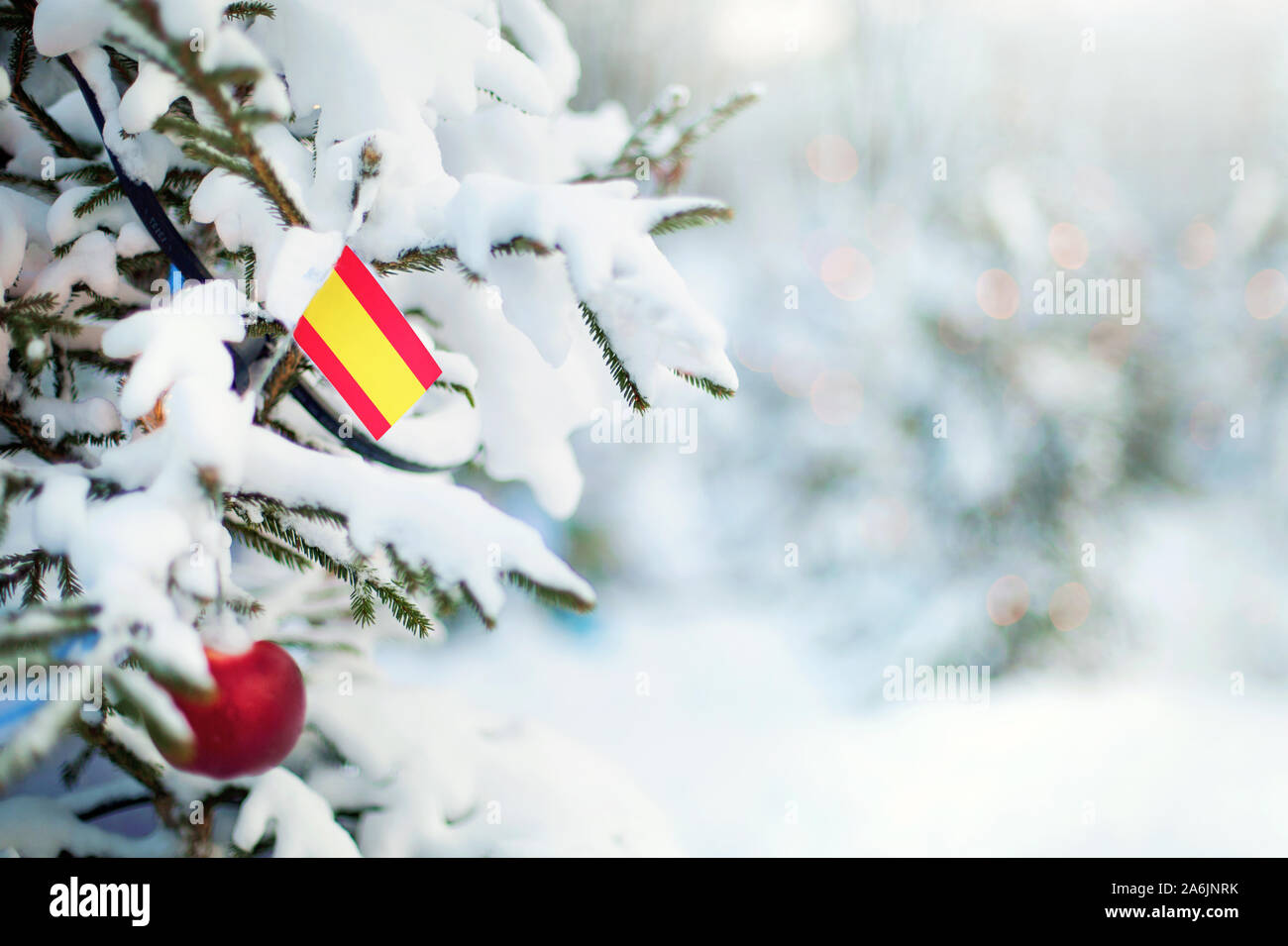 Weihnachten in Spanien. Xmas Tree mit Schnee, Dekorationen und eine Flagge bedeckt. Verschneite Wald Hintergrund im Winter. Weihnachten Grußkarte. Stockfoto