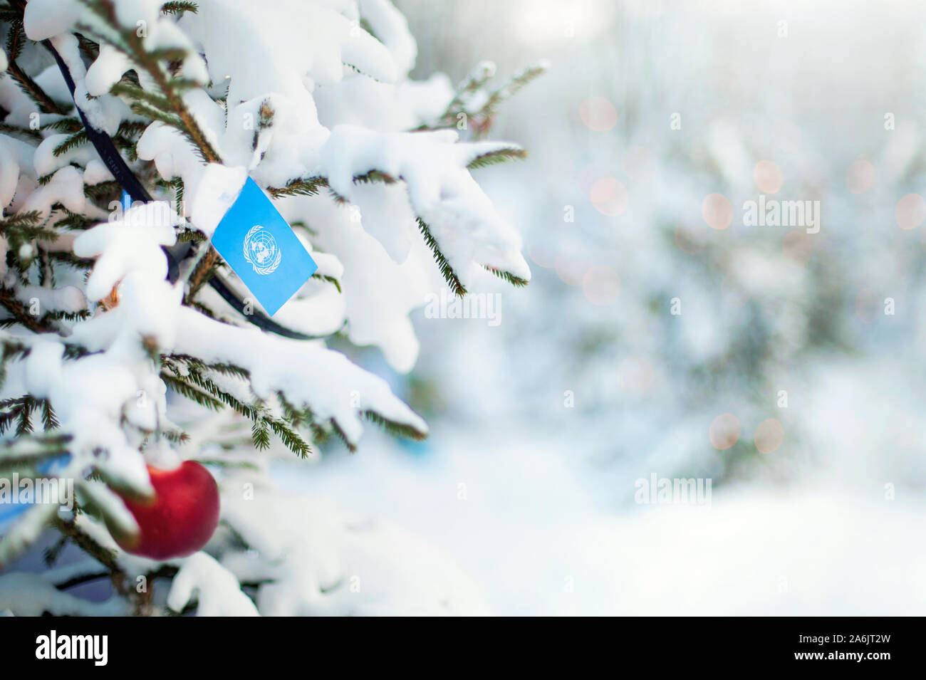 Weihnachten Vereinten Nationen. Xmas Tree mit Schnee, Dekorationen und eine Flagge bedeckt. Verschneite Wald Hintergrund im Winter. Weihnachten Grußkarte. Stockfoto