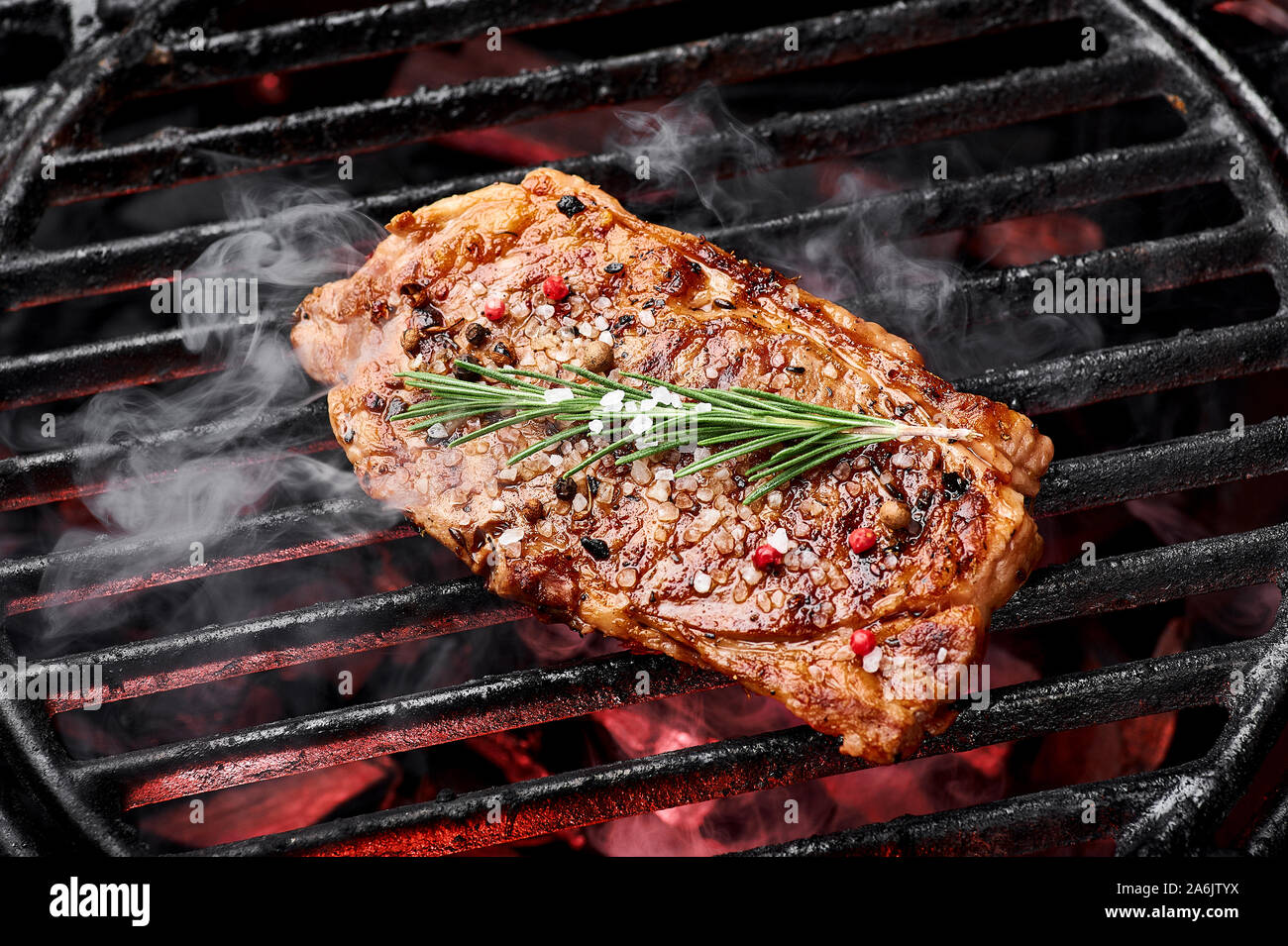 Rindersteak mit Meersalz, Gewürze und Rosmarin Braten im Grill. Rauchen Beef Steak im Grill. Stockfoto