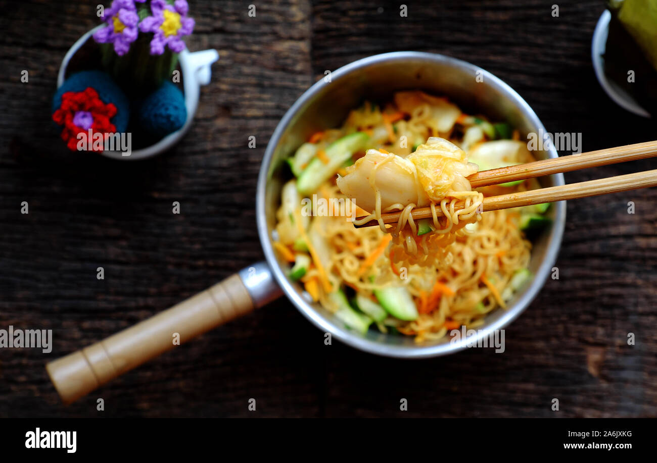 Ansicht von oben in der Nähe der menschlichen Hand mix Gelb trocken instant Nudeln mit Gemüse für schnelle Veganes Frühstück auf dunklem Hintergrund Stockfoto