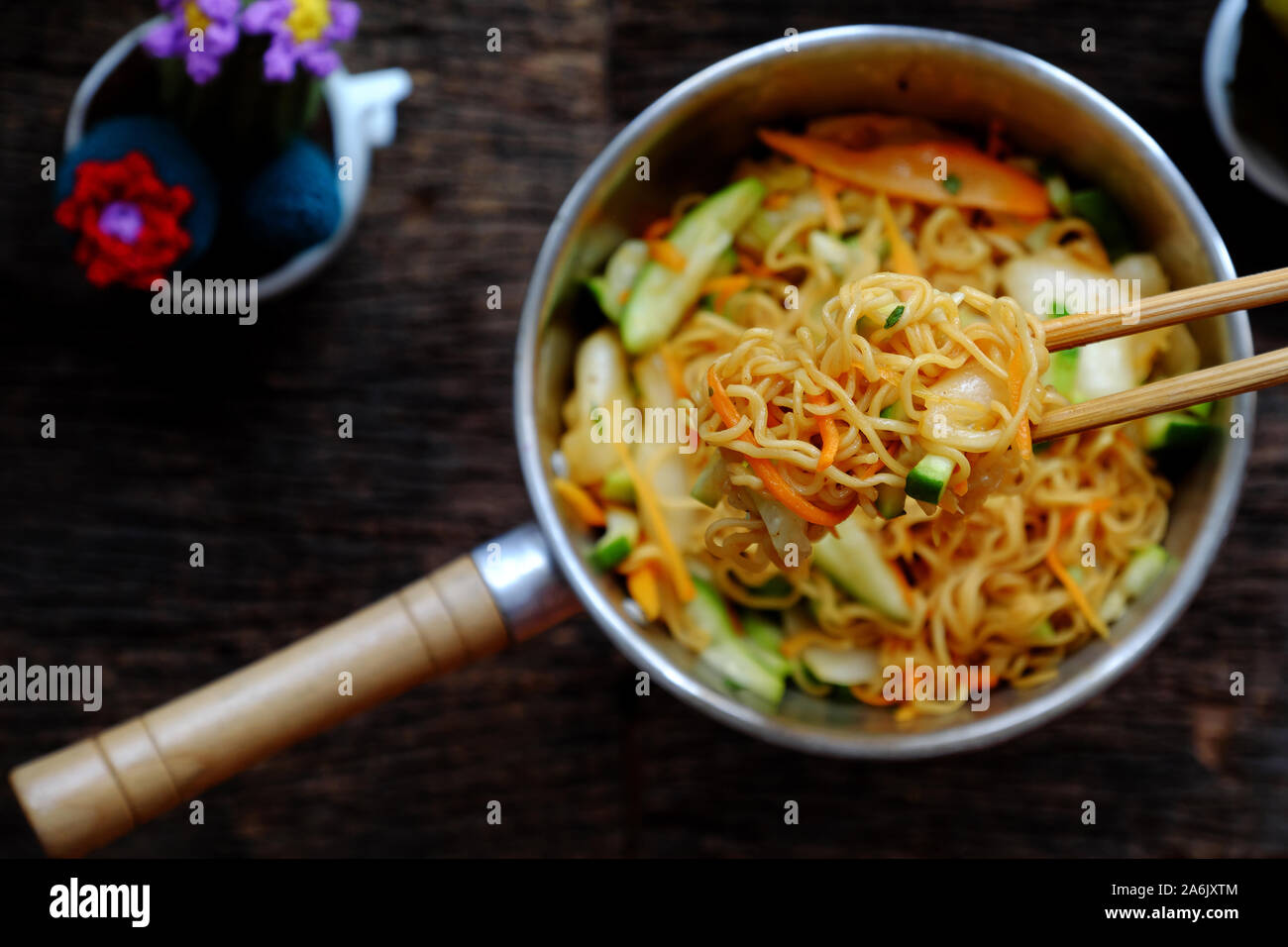 Ansicht von oben in der Nähe der menschlichen Hand mix Gelb trocken instant Nudeln mit Gemüse für schnelle Veganes Frühstück auf dunklem Hintergrund Stockfoto