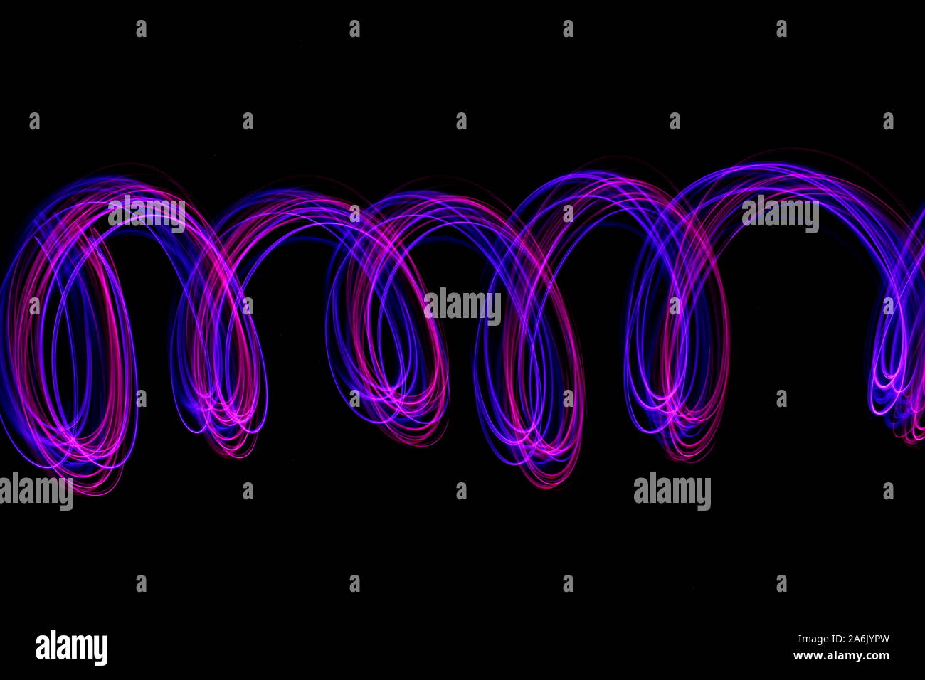 Lange Belichtung Foto von Neon Farbe in einer abstrakten Wirbeln, parallele Linien Muster vor einem schwarzen Hintergrund. Licht Malerei Fotografie. Stockfoto