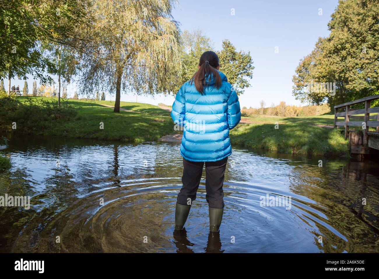 Nach dem Regen: Rückansicht eines weiblichen (tragen Gummistiefel) isoliert im Freien im Herbst Sonnenschein stehend im Wasser nach Tagen der ständige Regen in Großbritannien. Stockfoto