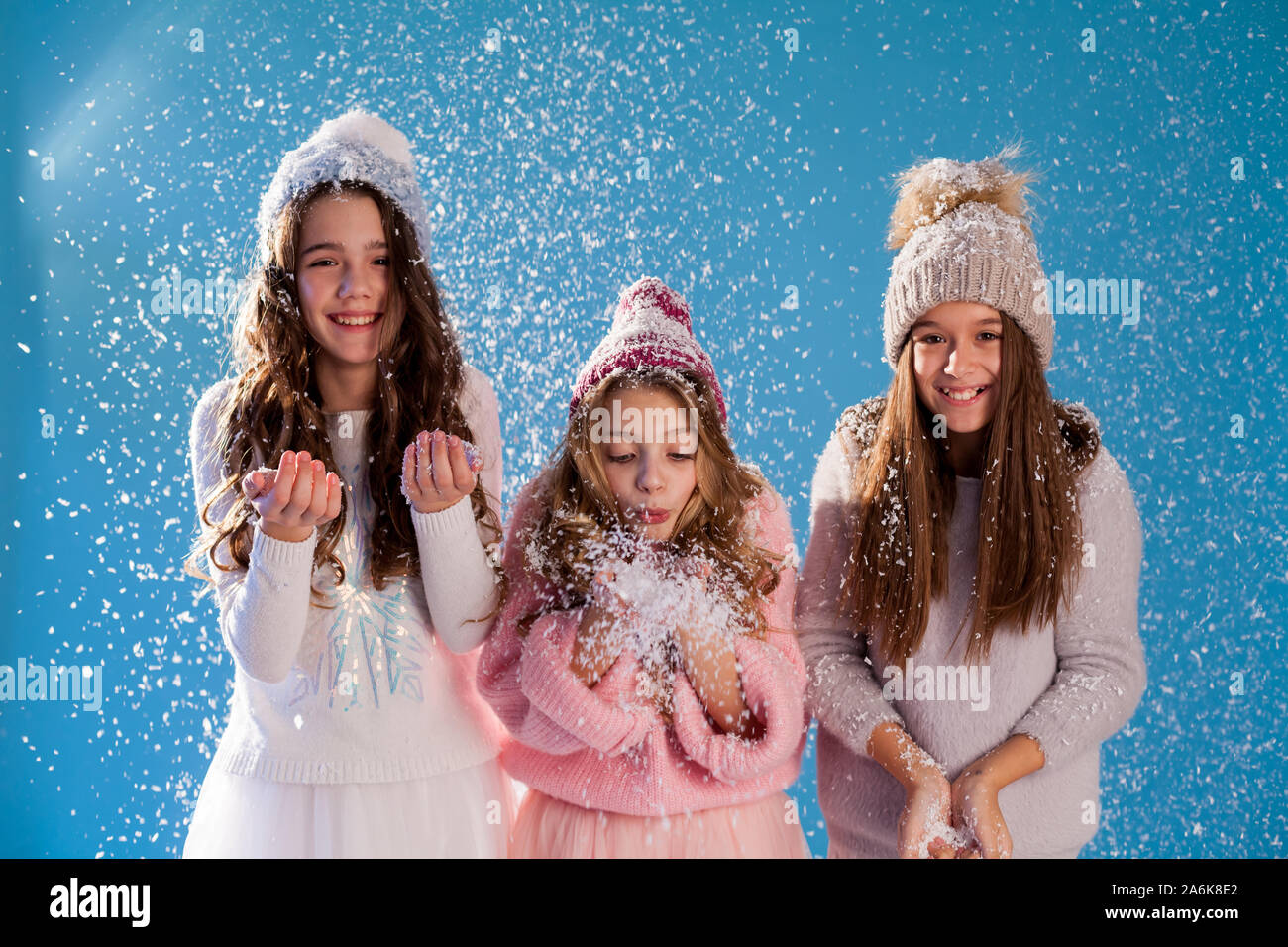 Drei modische schöne Mädchen im Winter Mützen spielen mit Schnee Stockfoto