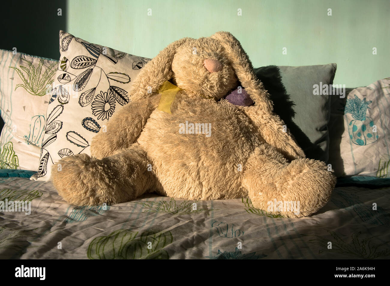 Riesige creme Teddybär stützte sich auf einem Bett. Stockfoto